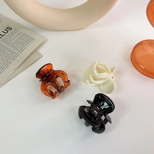 Three-piece hair claw clip set in black, cream, and amber tones on a minimal white surface