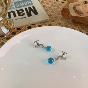 Detail of silver faucet earrings with hanging translucent blue crystal beads on white ceramic
