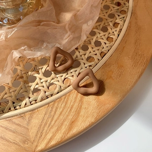 Detail view of brown matte irregular triangular earrings on a woven tray