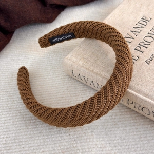 Détail d'un serre-tête tricoté marron montrant l'étiquette faite main et la texture