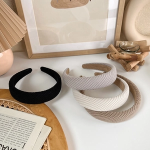 Detailed close-up of textured knitted headbands in black, grey, cream, and khaki colors