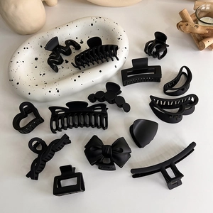 Lot de 12 pinces à cheveux noir mat aux formes géométriques et cœurs sur plateau blanc