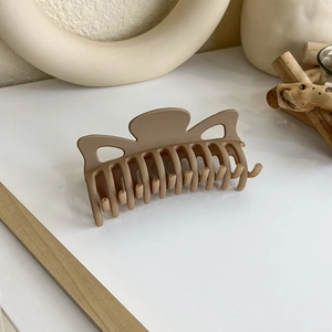 Détail d'une pince à cheveux mate café sur un support en bois au style minimaliste