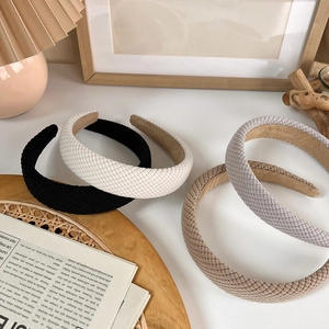 Close-up of four thick knitted sponge headbands in black, beige, khaki, and light grey