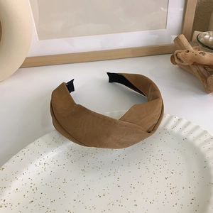 Detail eines braunen gefalteten PU-Leder-Stirnbands mit Knoten auf edlem Keramiktablett