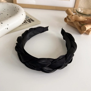 Gros plan d'un serre-tête tressé en satin noir avec une texture épaisse de style français