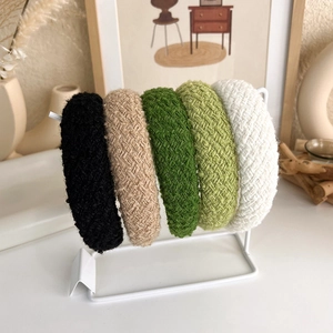 Braided padded headband set in assorted knit colors on a display stand for women