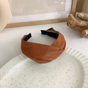 Detail eines karamellfarbenen Kunstleder-Stirnbands mit Knotendesign und Faltenstruktur