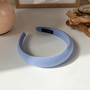Detailed close-up of light blue knitted headband with a handmade textile label