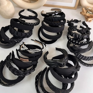 Detail view of various black French-style headbands with pearls and braided textures