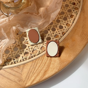 Close-up of retro caramel resin stud earrings displayed on a rustic woven tray