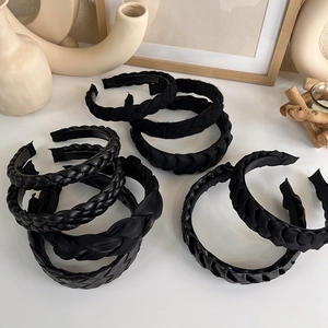 Close-up of black braided headbands showing leather, satin and matte knit textures
