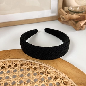 Close-up of wide black headband featuring dense diagonal knit texture and smooth inner lining