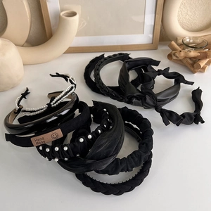 Detail view of black headband set with handmade label, pearls, and knit textures