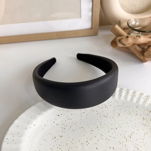 Detailed macro view of black faux leather headband with premium lychee texture and thick padding