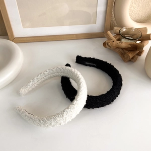 Detail view of woven tweed padded headbands with handmade label on beige background