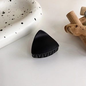 Détail d'une grande pince à cheveux noire mate avec un design géométrique minimaliste