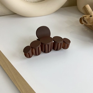Détail d'une pince à cheveux mate marron chocolat avec un design à cinq segments circulaires