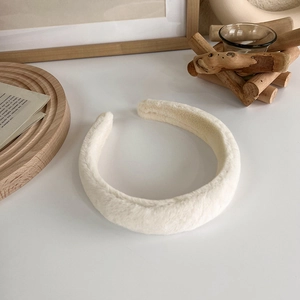 Détail d'un serre-tête épais en peluche crème avec texture douce pour soins du visage