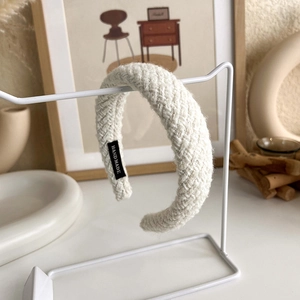 Macro detail of white hand-knitted thick headband with soft wool texture and handmade label