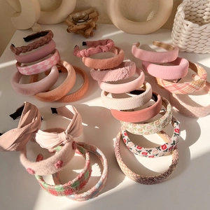 Detail shot of various pink plush sponge headbands with diverse knitted and floral patterns