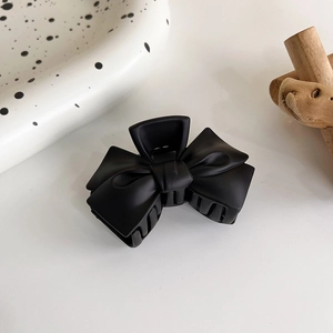 Gros plan d'une grande pince à cheveux nœud noir mat avec une élégante texture plissée