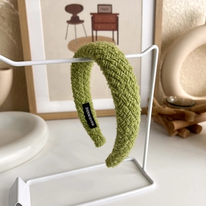 Detailed macro of green woven headband featuring a handmade fabric label on the inner side