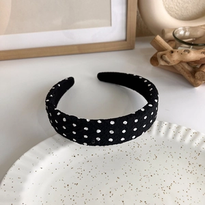 Detailed close-up of a black and white polka dot headband on a decorative plate