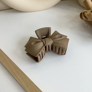 Détail de la pince à cheveux marron mat en forme de nœud avec texture givrée et ressort