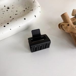 Grosse pince à cheveux rectangulaire noir mat vue de près sur fond minimaliste
