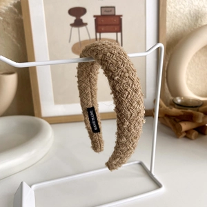 Detail of khaki woven headband with handmade label on minimalist display stand