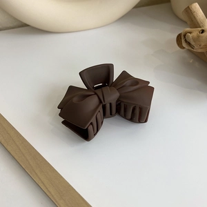 Gros plan détaillé de la pince à cheveux nœud marron foncé mat avec texture givrée
