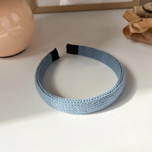 Close-up of light blue knitted headband with textured cable pattern and soft fabric