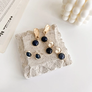 Detail of vintage gold earrings set with deep blue gems on a stone base display