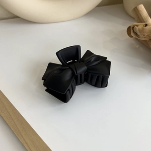 Gros plan d'une pince à cheveux noire mate en forme de nœud avec finition givrée