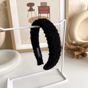 Detail view of handmade black fuzzy knit headband with textured bouclé fabric on display