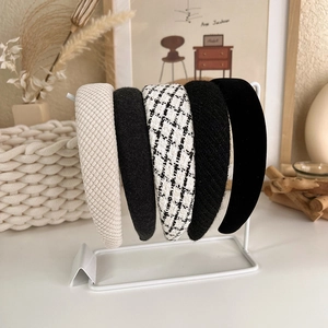 Detail view of five checkered and tweed headbands on a white decorative display stand
