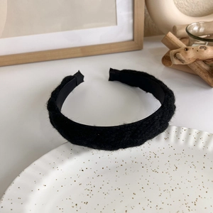 Detail shot of the black bouclé knit texture and inner lining of the thick padded headband