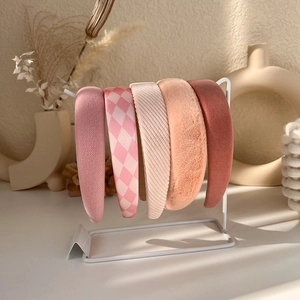Detail of pink sponge headbands in various knit and plush textures on a display rack