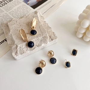 Minimalist Klein blue drop earrings set in vintage gold finish on white marble base
