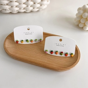 Detail shot of colorful strawberry stud earrings set on jewelry card on wood tray