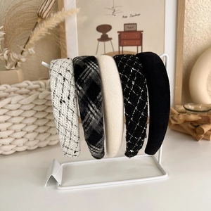 Close-up of five French style tweed and padded headbands on a white metal display stand