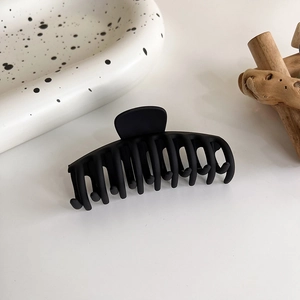 Détail d'une grande pince à cheveux noire mate avec dents en résine pour une tenue forte