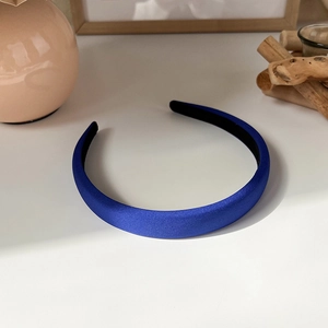 Detail view of the vibrant royal blue wide satin headband on a clean white surface