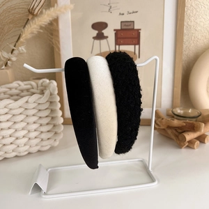 Close-up of elegant black velvet and white tweed headbands displayed on a metal stand