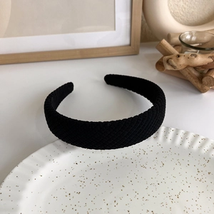 Detail of black knitted headband with textured fabric on a white ceramic tray