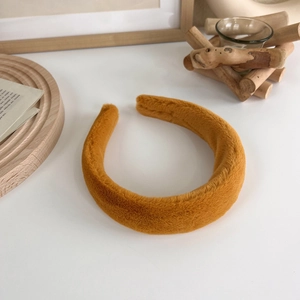 Détail d'un serre-tête épais en peluche jaune gingembre avec texture en fausse fourrure