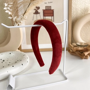 Détail d'un serre-tête large en velours rouge présenté sur un support blanc