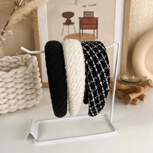 Close-up of three textured headbands in black rhomboid, white tweed and plaid patterns