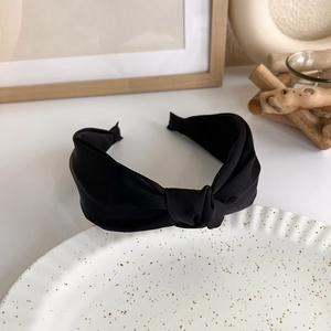 Close-up detail of the black twisted knot fabric headband with soft matte texture